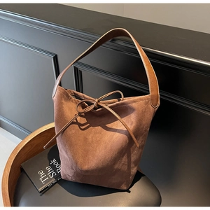 Detail of vintage brown suede tote bag with decorative bow on a leather chair