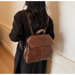 Detailed view of vintage brown leather backpack texture and side drawstring on a model