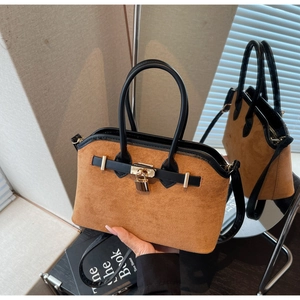 Gros plan du sac en daim marron avec boucle dorée et finitions en cuir noir
