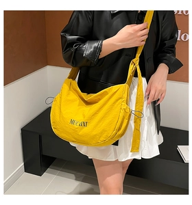 Détail du sac bandoulière en nylon jaune avec cordon de serrage et bandoulière nouée