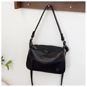 Detail of black faux leather shoulder bag with triple zippers and silver metal logo