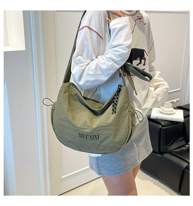 Détail d'un sac demi-lune en nylon vert olive avec cordon réglable et tirette de zip tissée
