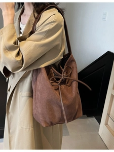 Retro dark brown suede tote bag with bow detail worn by model in casual street style