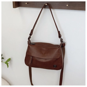 Detail of vintage brown shoulder bag with metal logo, zipper, and dual strap options