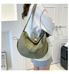 Détail du sac demi-lune en nylon vert olive montrant la texture lisse et le logo