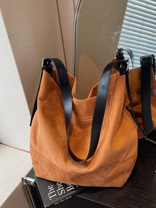 Large caramel suede tote bag with black leather straps shown in a warm indoor setting