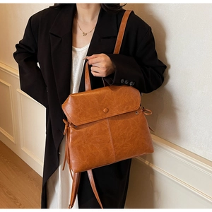 Close-up of vintage brown PU leather backpack featuring side bow drawstring details