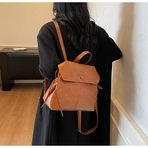 Rear view of brown leather vintage backpack showing adjustable straps on female model