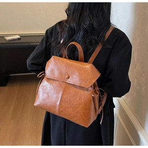 Rear view of a model wearing the brown vintage faux leather backpack with side bow details