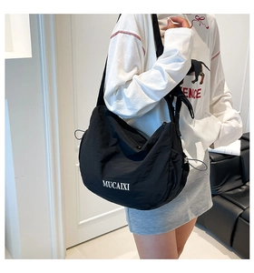 Détail du sac bandoulière en nylon noir imperméable avec cordon et large bandoulière