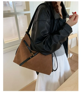 Detail of vintage brown suede tote bag with leather straps on a model in leather jacket