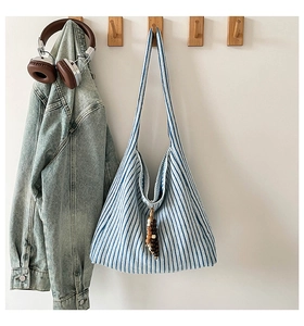 Close-up of blue and white striped knit tote bag with wooden bead tassel on a wooden hook