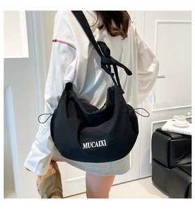 Détail du sac à bandoulière noir en nylon avec nœud papillon et grande forme de croissant