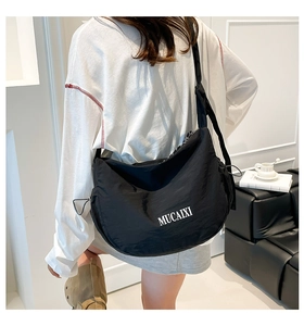 Détail du sac croissant en nylon noir avec imprimé lettres blanches et plis texture
