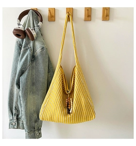 Detailed close-up of yellow and white striped knitted tote bag with wooden bead charm