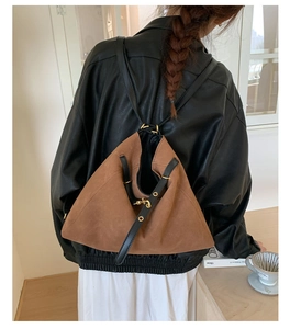 Brown frosted leather bucket bag worn as a backpack by a model in a modern interior
