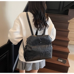 Detail of black vintage faux leather backpack showing soft texture and drawstring on model