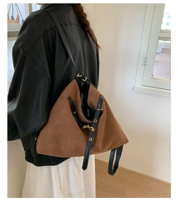 Detailed side view of a large brown suede tote bag with black leather straps and gold studs