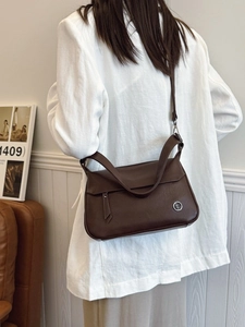 Retro caramel brown leather shoulder bag with circular metal logo and tassel details