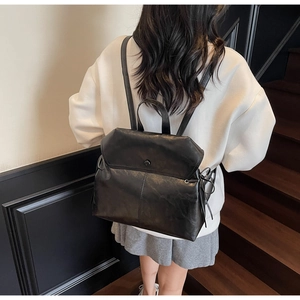 Detail of minimalist black soft leather backpack with drawstring and magnetic closure flap