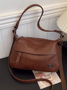 Vintage brown leather crossbody bag with adjustable strap on a minimalist desk