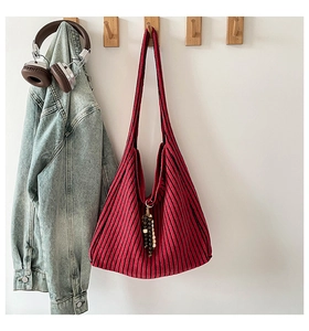 Detail of red and black striped knitted tote bag with wooden bead fringe hanging on a wall