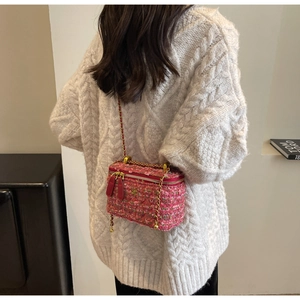 Detail of pink tweed mini chain bag worn by a model in a cozy white oversized sweater