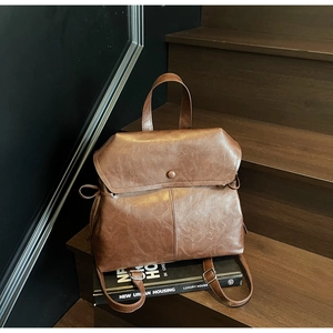Detail of vintage brown PU leather backpack on stairs with matte texture and flap closure