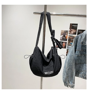 Détail de la bandoulière nouée et du cordon de serrage sur ce sac besace noir en nylon