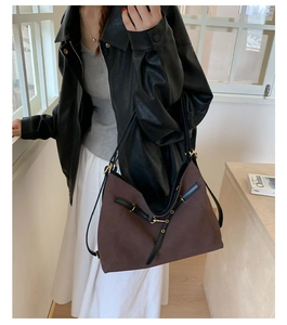 Detail of brown canvas tote bag with black leather straps and golden metal buckles
