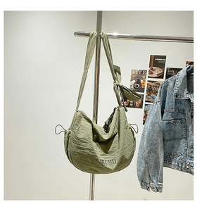 Détail du sac croissant vert avec décoration de nœud et tissu en nylon texturé