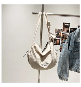 Détail d'un grand sac bandoulière beige avec nœud décoratif sur la bandoulière réglable