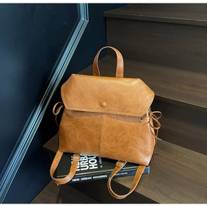 Brown vintage leather bucket backpack on wooden stairs with an urban aesthetic