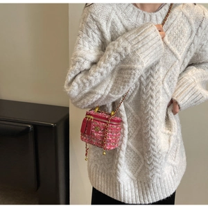 Detail of pink tweed mini box bag with metal chain strap and flower charm