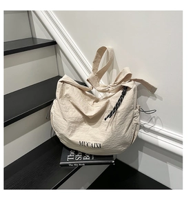 Détail du sac hobo montrant le tissu plissé, la bandoulière nouée et le logo MUCAIXI