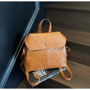 Caramel retro faux leather backpack with drawstring details displayed on wooden stairs