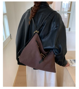 Detail view of large dark brown tote bag with leather straps on a fashion model