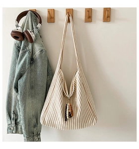 Detail of striped knit shoulder bag with decorative wooden beads and tassel accent