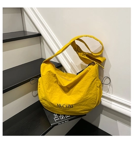 Gros plan du sac croissant en nylon jaune vif sur des marches avec livre de décoration