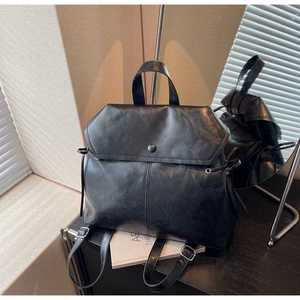 Side view of vintage black faux leather backpack with drawstring and flap closure
