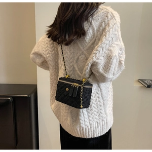 Detailed texture of black quilted chain bucket bag with a golden floral emblem detail