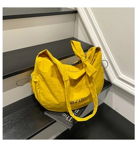 Détail du sac bandoulière en nylon jaune avec sangle nœud et cordon de serrage