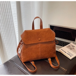 Detail of vintage brown leather backpack with drawstring closure and stylish flap buckle