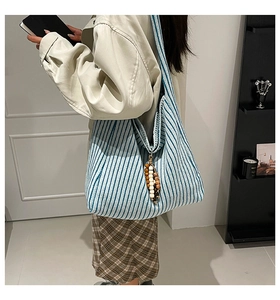 Detail of blue striped knitted tote bag with decorative leopard print beads on the side