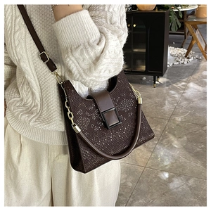 Detail of dark brown faux snakeskin texture on a luxury shoulder bag with metal chain