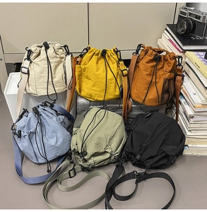 Close-up of drawstring nylon crossbody bags in multiple colors with mesh side pockets