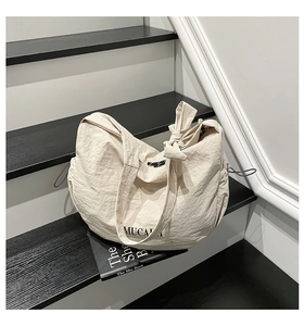 Détail du sac cabas en tissu froissé beige avec nœud et marquage MUCAI chic