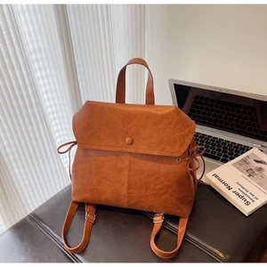 Detailed top view of a brown vintage leather backpack next to a silver laptop