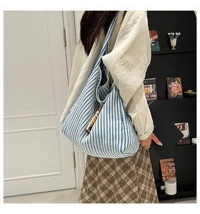 Detail of blue and white striped tote bag with beaded wood charm hanging on the handle