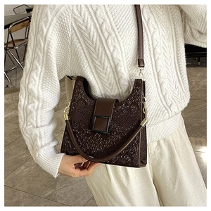 Detail of dark brown embossed texture crossbody bag worn with white knit sweater